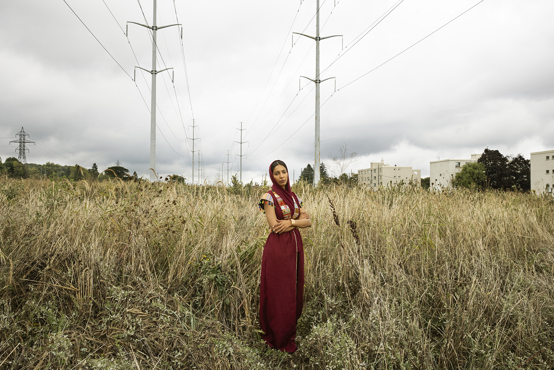 For Huda: a girl standing in the middle of the field wearing a red traditional dress.