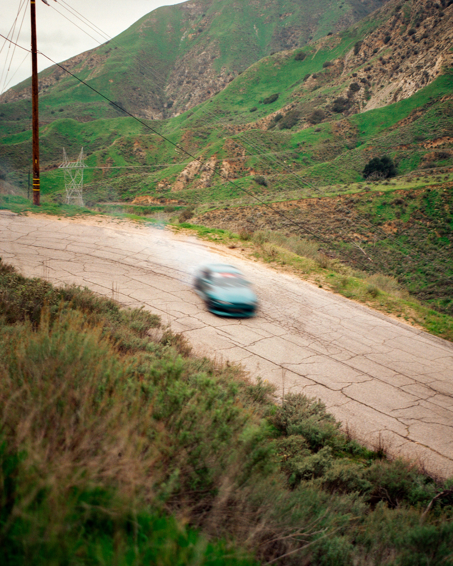 A car doing a drift on a road in the mountains.