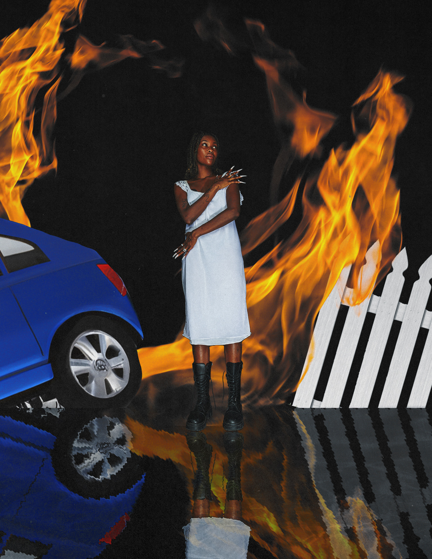 A person stands in the middle of the photograph while being surrounded by flames, to the left of them is the back end of a car and to the right of them a white picket fence. The bottom quarter of the image is reflected