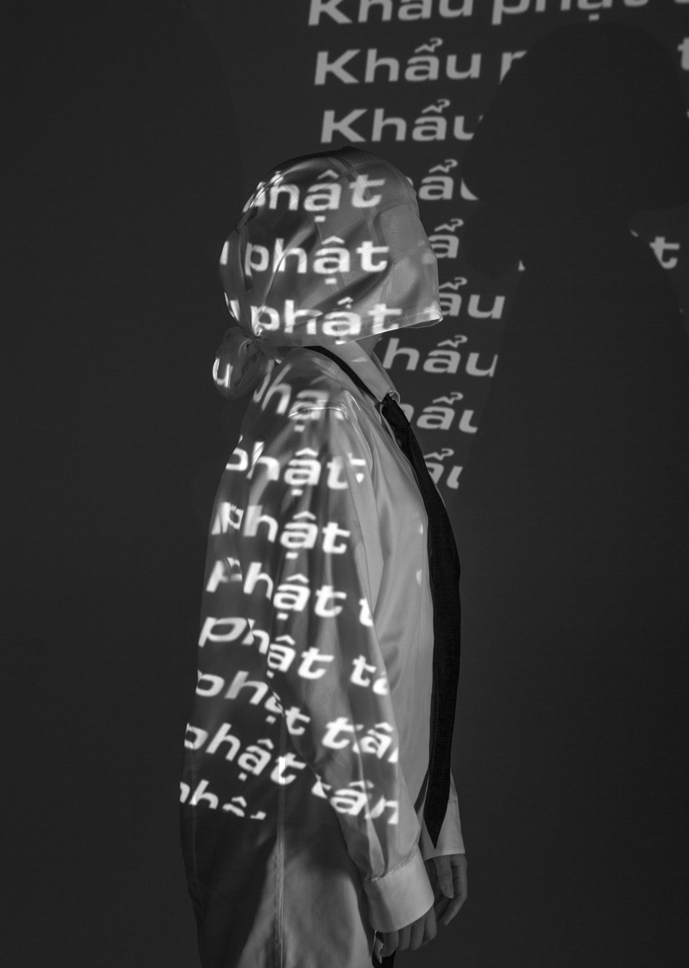 A profile of a white masked person, with words being projected onto them