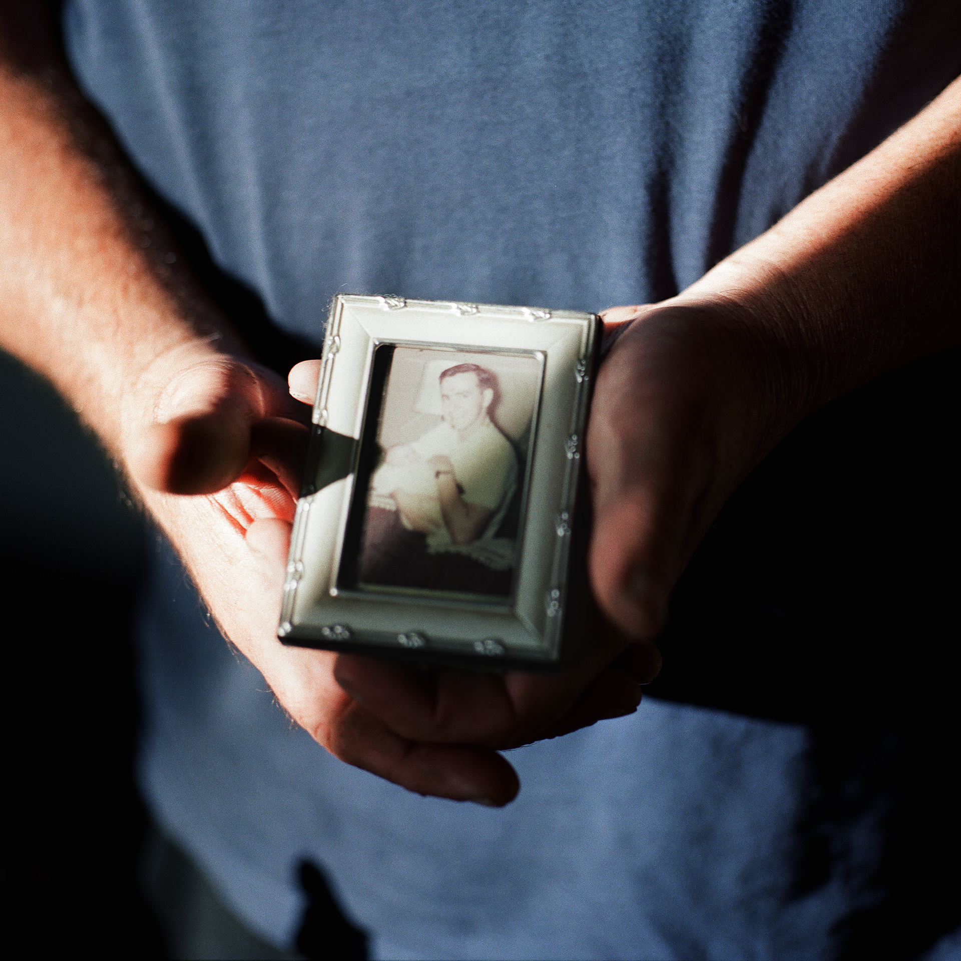 A man holding a photo of his late father.