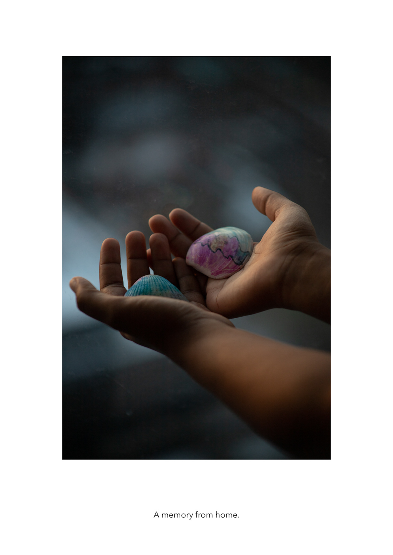 Olivia Gentil The photo depicts a pair of hands holding a seashell in each hand. The seashells are colored pink and blue. The surrounding part of the image is blurred, solely focused on the two hands.