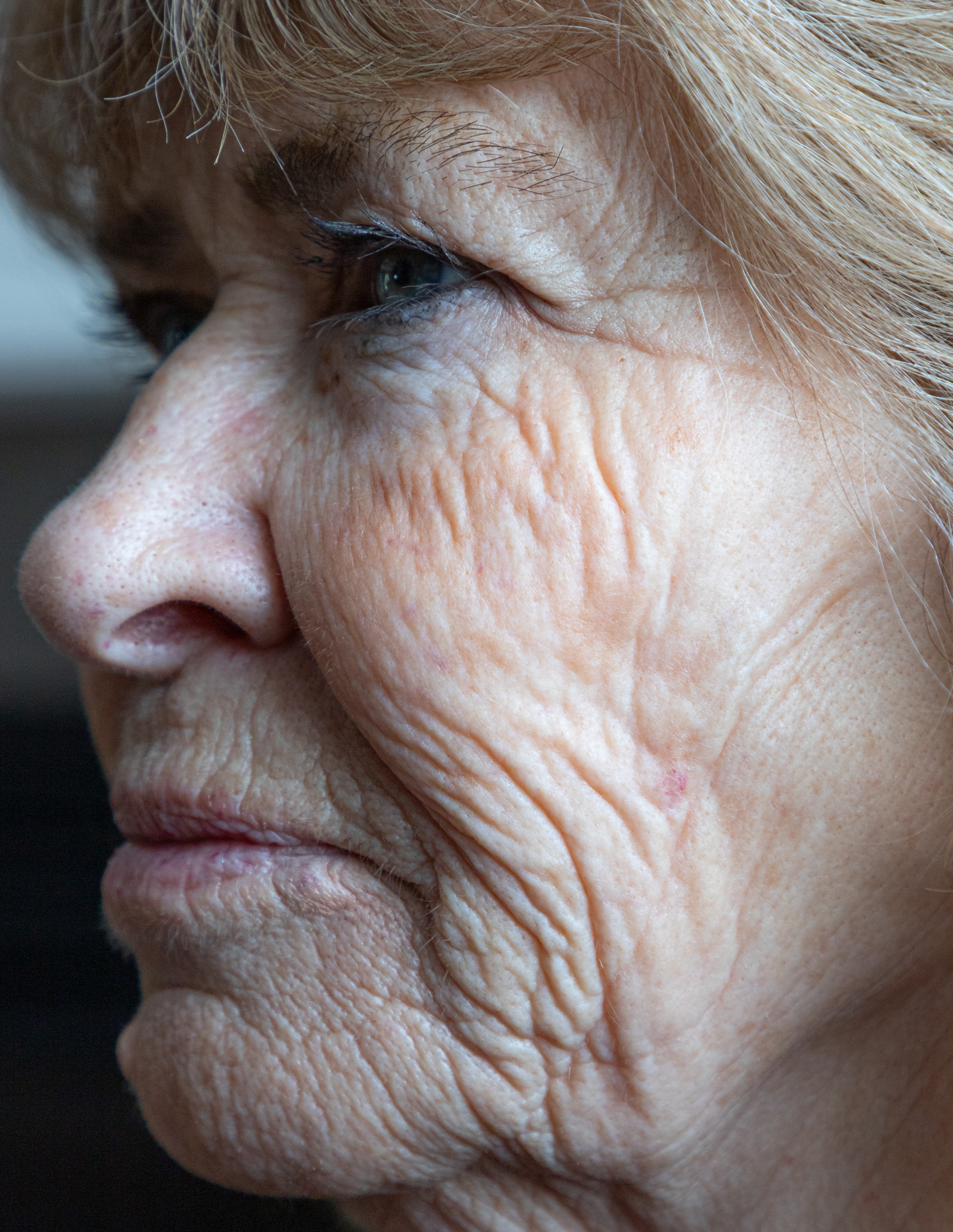 A close up of a person's profile of their face, a strong emphasis on their wrinkles and various textures of their face