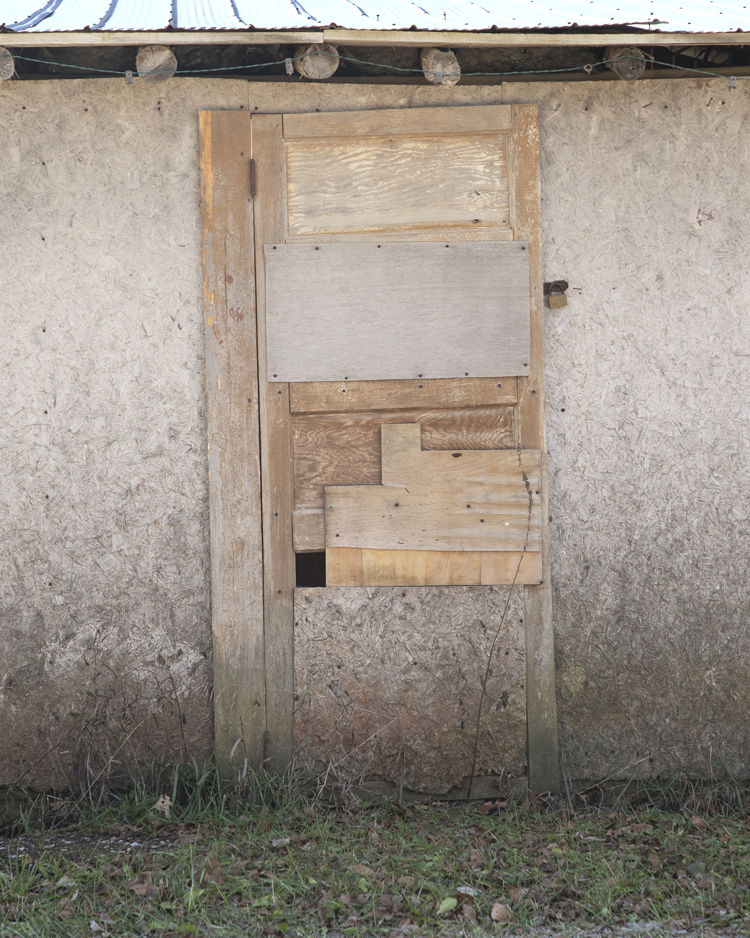 Door: A broken down and mended wooden door fills the frame.