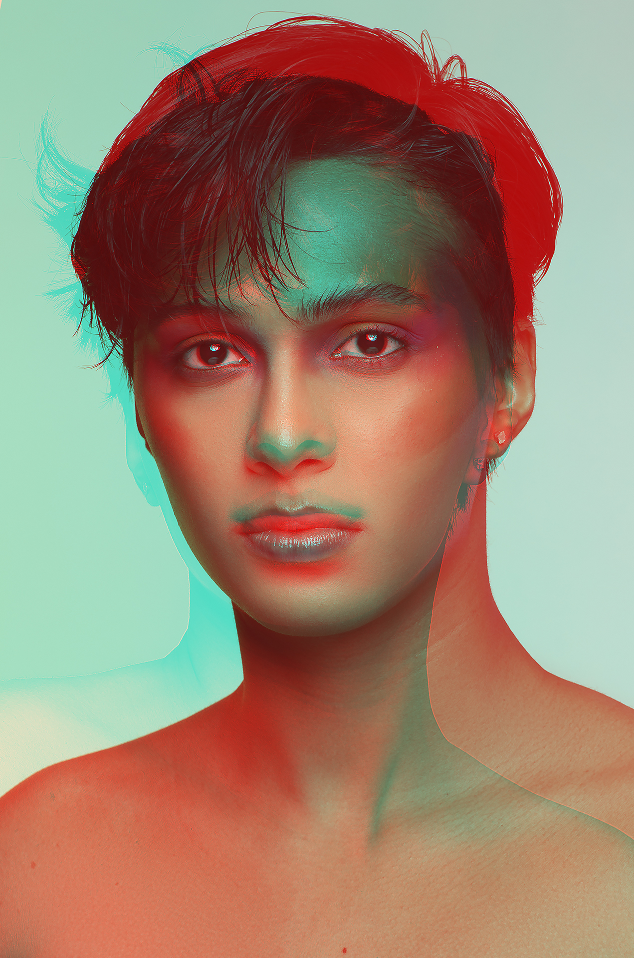 Two headshot portraits of the same girl stacked on top of each other to create a double exposure. One portrait is red and the other is cyan. The eyes are aligned, the model has short hair and her collarbones are exposed.