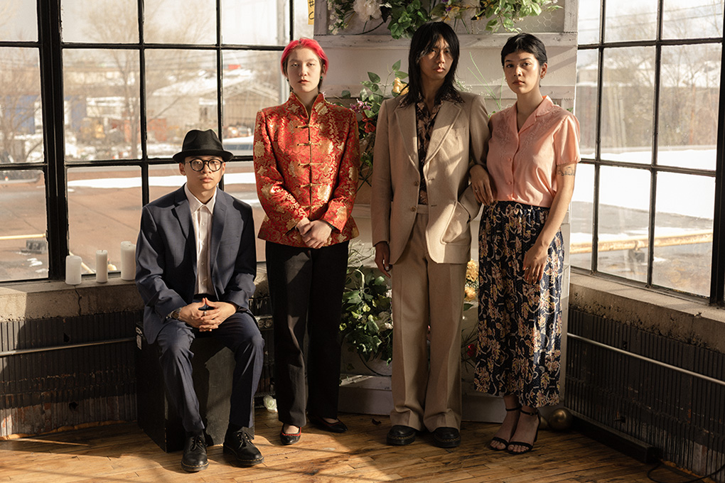 A group family portrait of 4 Asian people, dressed in formal clothing.