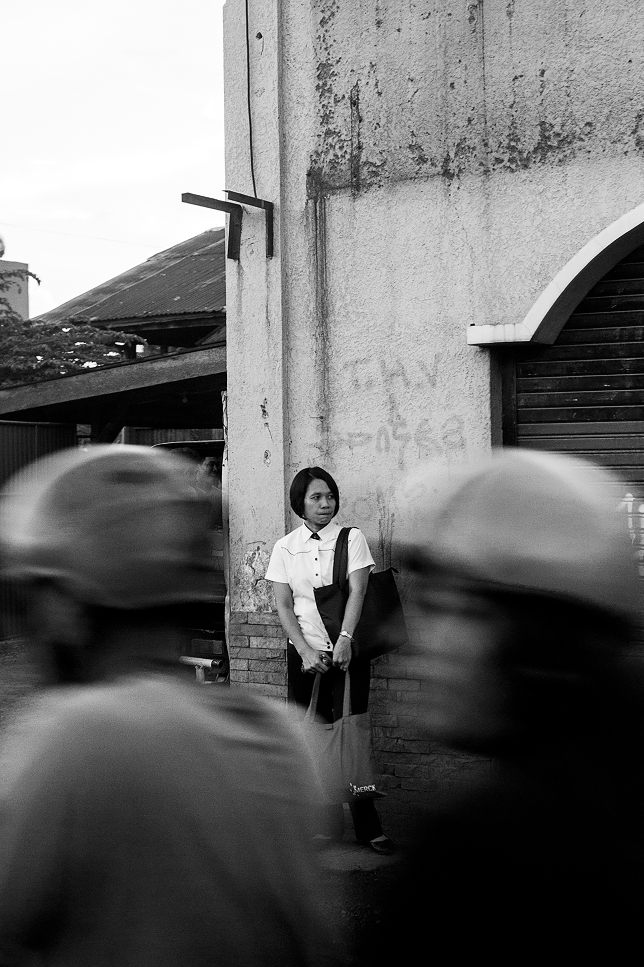 Bus Stop - A woman waits at a bus stop as new motorcycle taxi passes by in Cebu, Philippines.