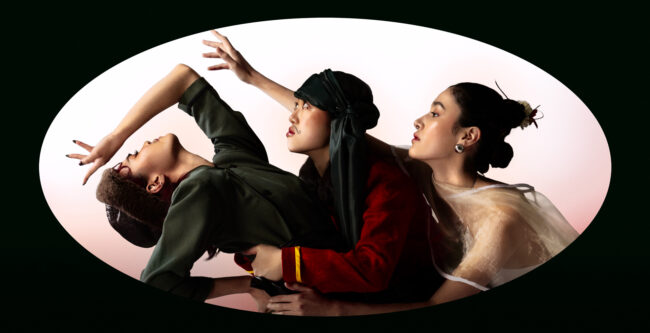 Image of 3 women wearing moustache makeup and asia traditional clothes. Model 1 (first from left to right), is looking up. The other models are looking in the same direction towards the left. Bright red-gradient background. Dark green, sharp oval frame is overlayed on top of the composition.