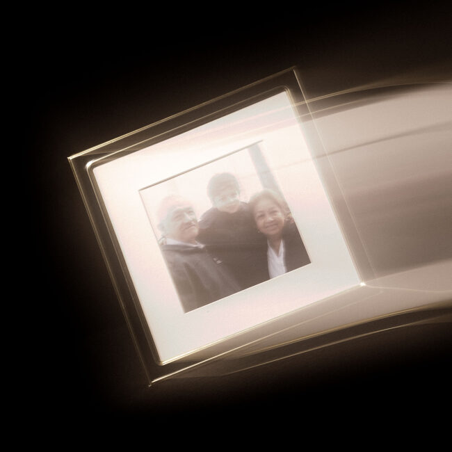 A photo of a picture frame containing an image of a child and his grandparents. The frame produces motion and light streaks as though it were being flung from the right side of the picture into a blank space.