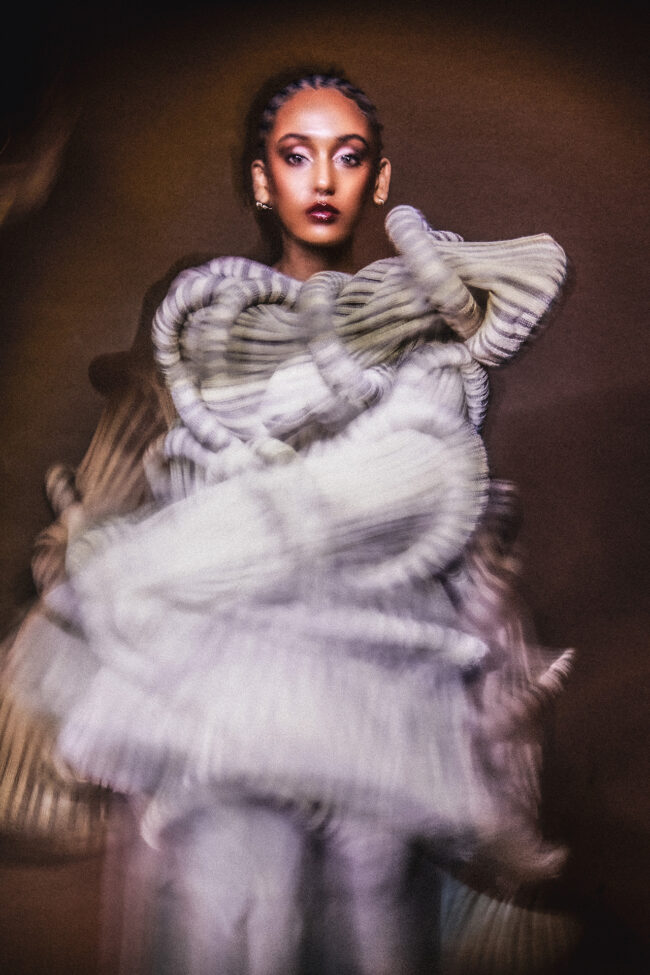 Image of model standing. The model's clothes are blurry.