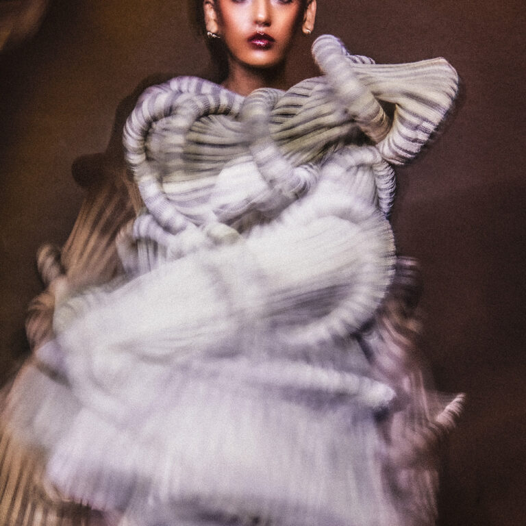 Image of model standing. The model's clothes are blurry.